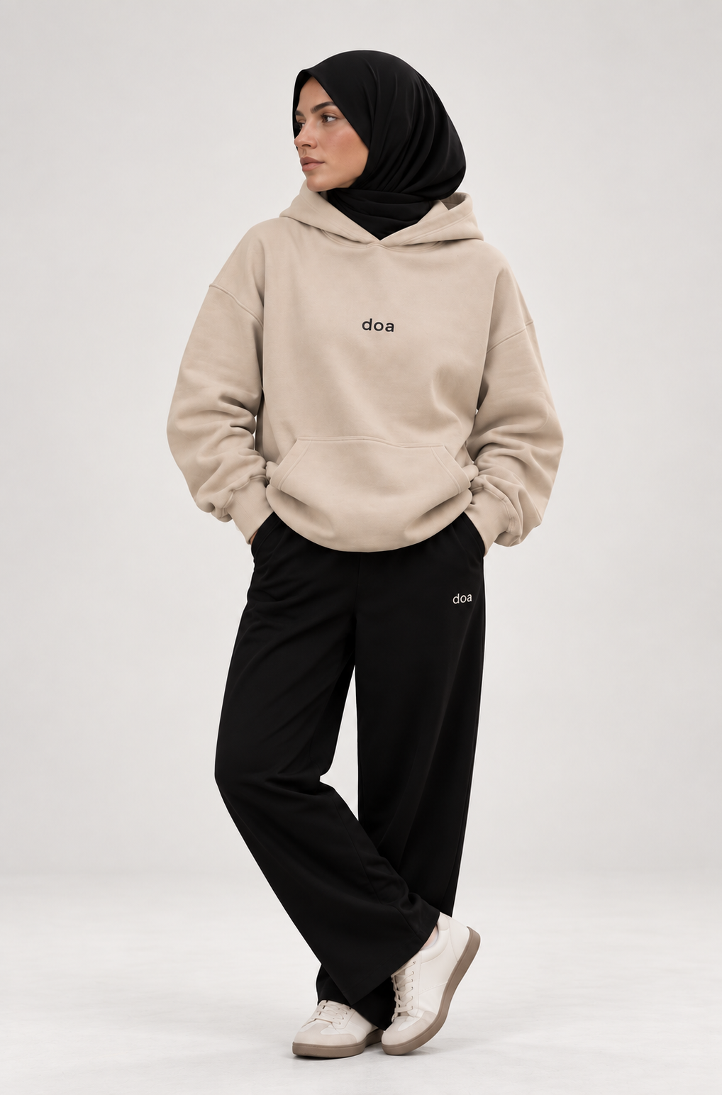 Woman in hijab wearing doa oversized beige hoodie with black relaxed trousersrs