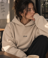 Woman wearing doa oversized beige hoodie in a café, close-up