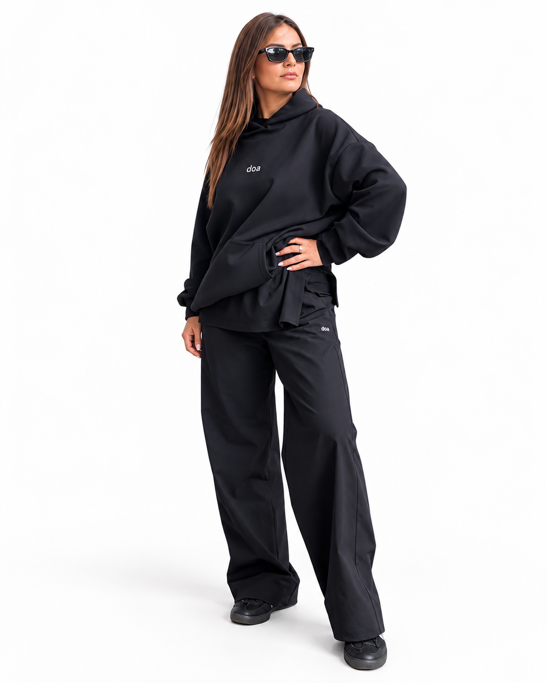 Woman wearing doa oversized black hoodie and relaxed trousers, side view