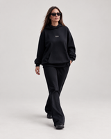 Woman wearing doa oversized hoodie in black with black relaxed trousers, front view
