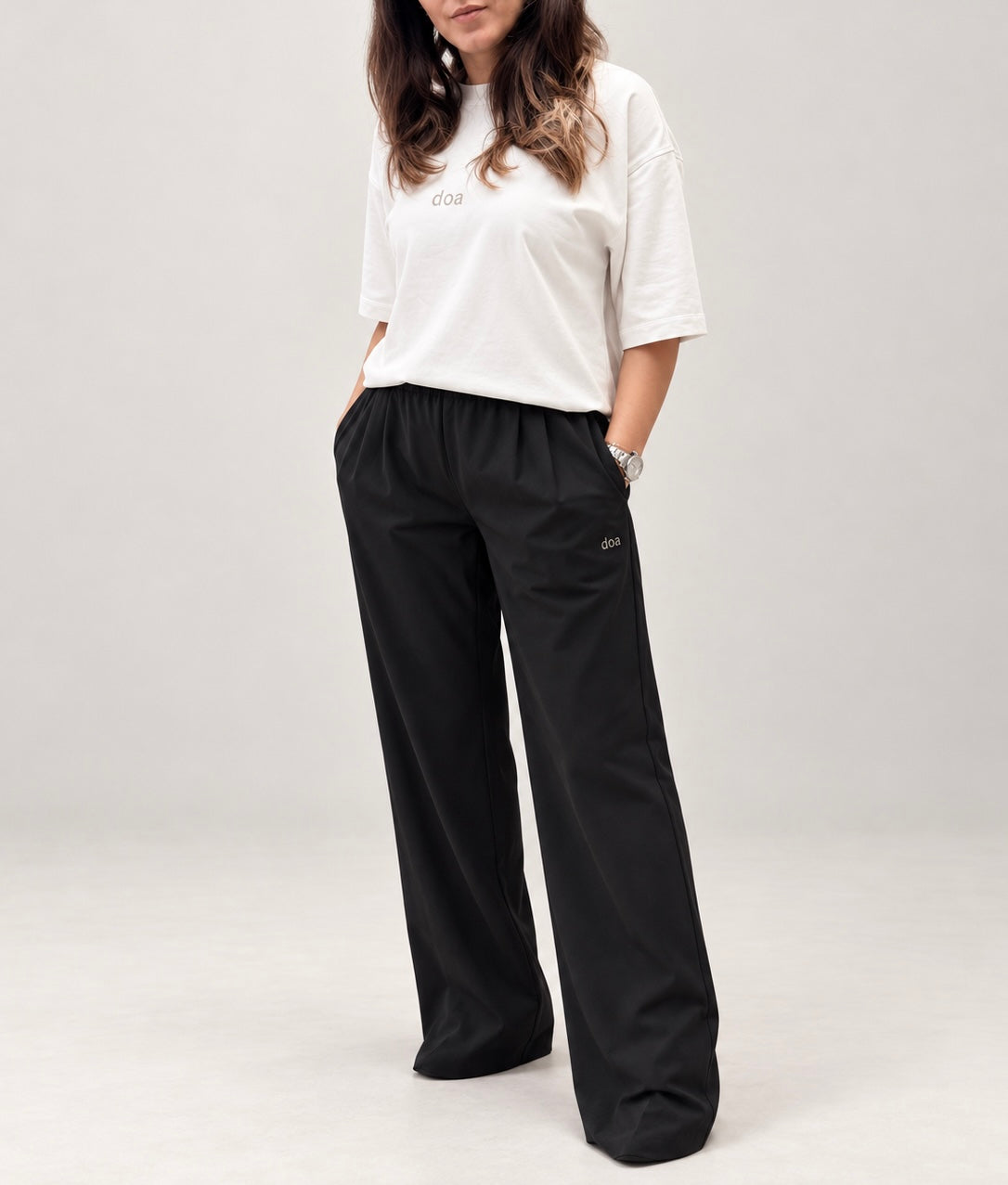 Woman wearing doa off-white oversized tee with black relaxed wide-leg trousers, front view