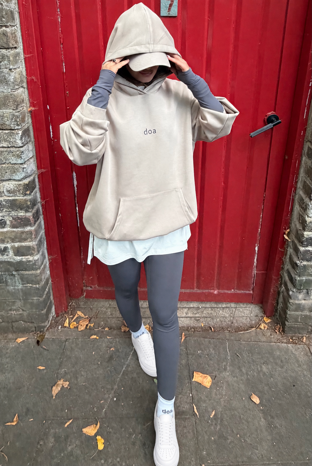 Woman wearing doa oversized beige hoodie with hood up, street style