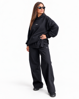 Woman wearing doa oversized black hoodie and relaxed trousers, side view