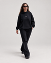 Woman wearing doa oversized hoodie in black with black relaxed trousers, front view