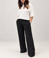Woman wearing doa off-white oversized tee with black relaxed wide-leg trousers, front view